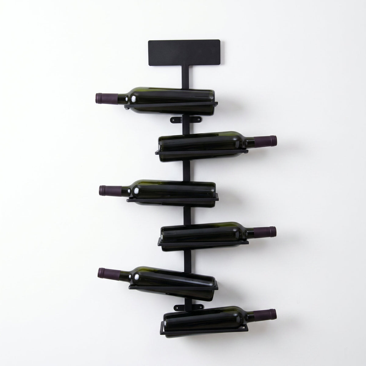 Porte-bouteille mural en fer noir avec quatre bouteilles sur fond blanc