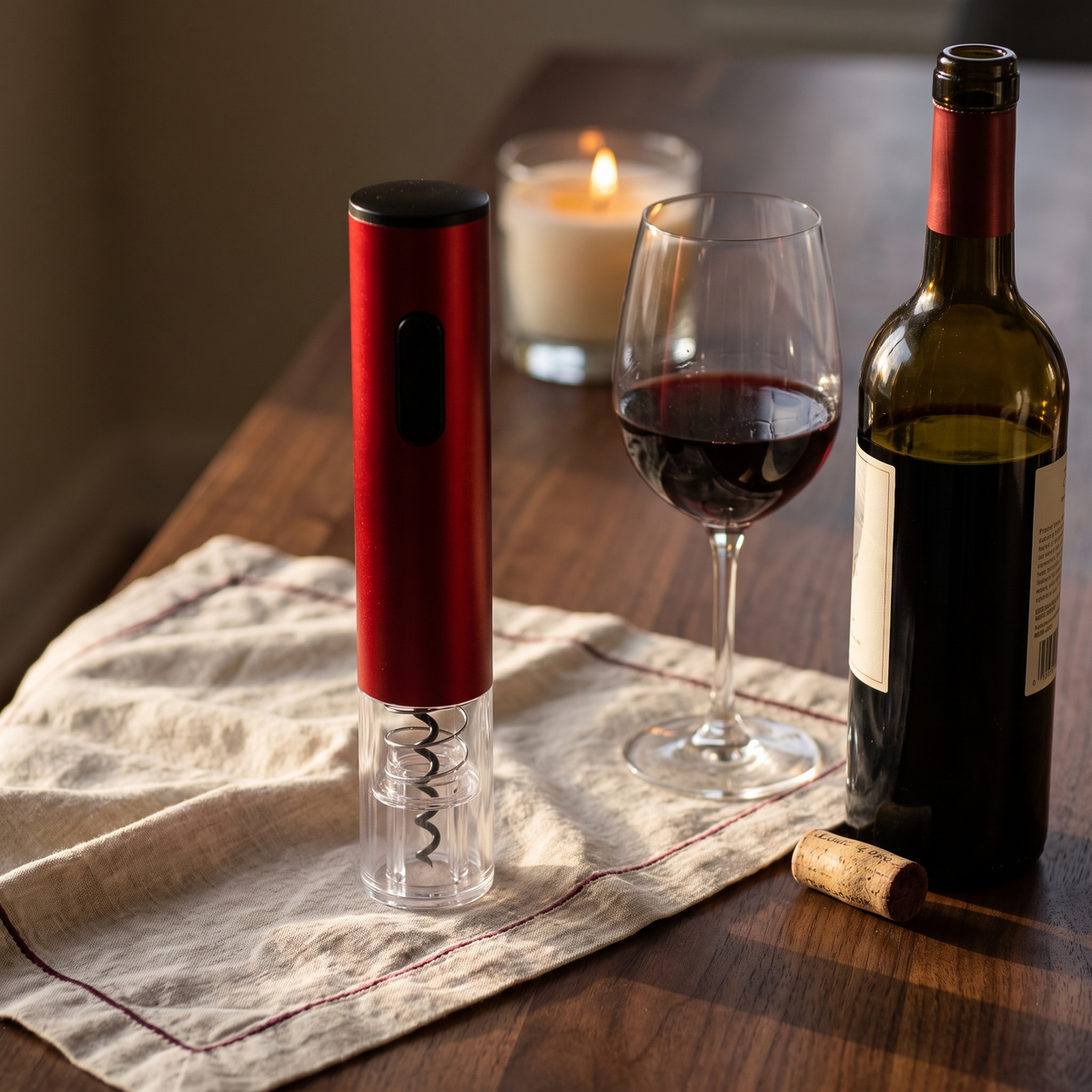 Tire-bouchon électrique rouge sur table en noyer avec bouteille et verre de vin