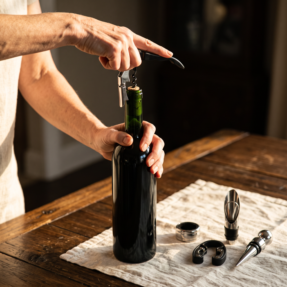 Ouverture d'une bouteille de vin avec le limonadier du kit, accessoires posés sur la table