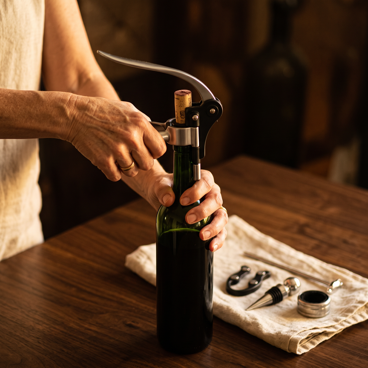 Ouverture d'une bouteille de vin avec le tire-bouchon à levier du coffret tiroir, accessoires sur la table