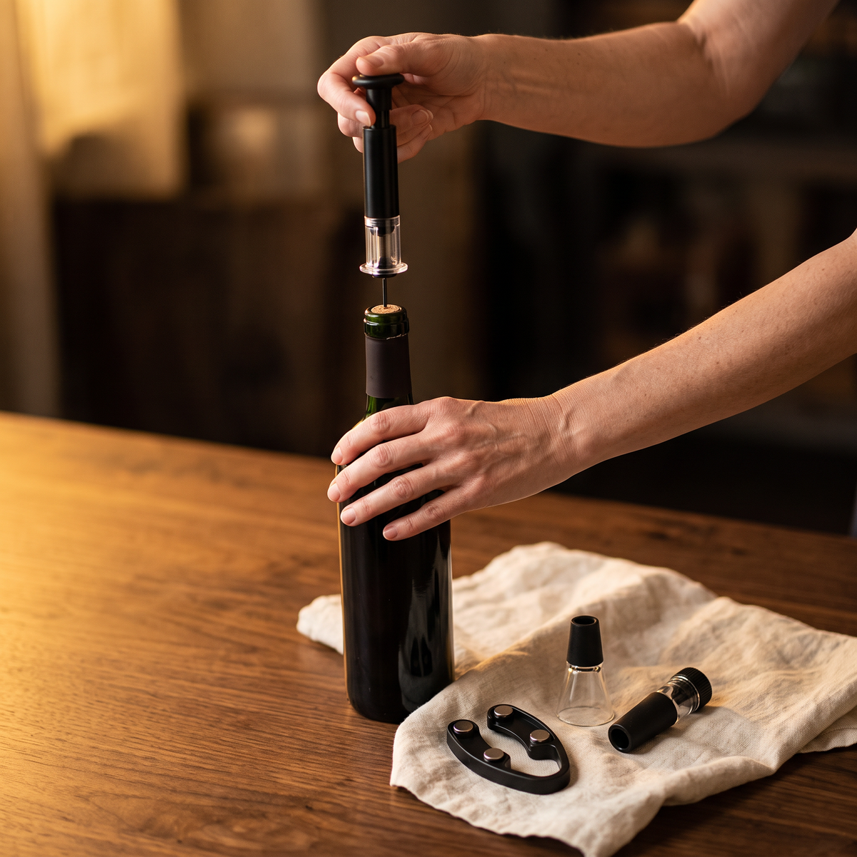 Ouverture d'une bouteille de vin avec le tire-bouchon à air du coffret cadeau, accessoires sur la table