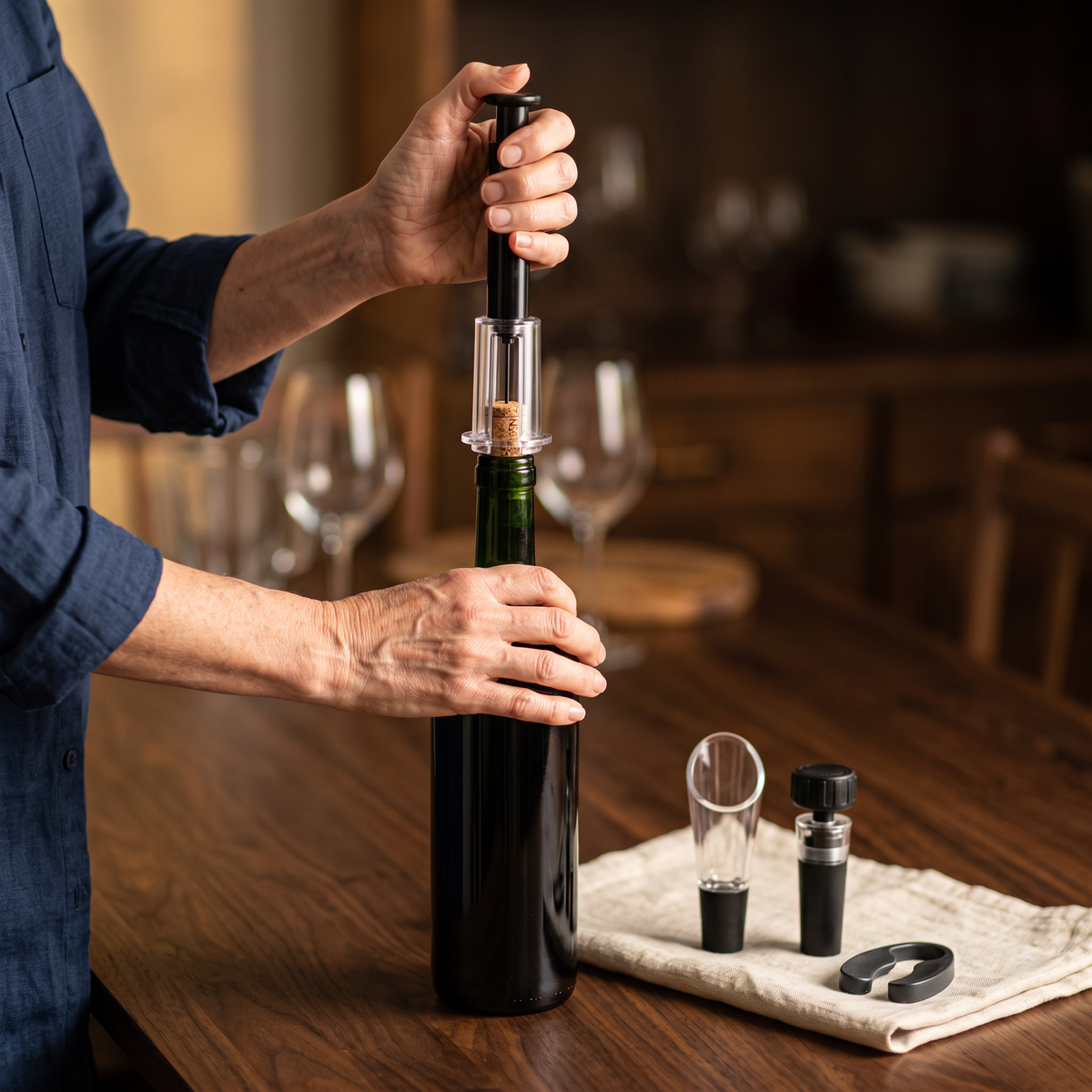 Ouverture d'une bouteille de vin avec le tire-bouchon à air professionnel, accessoires sur la table