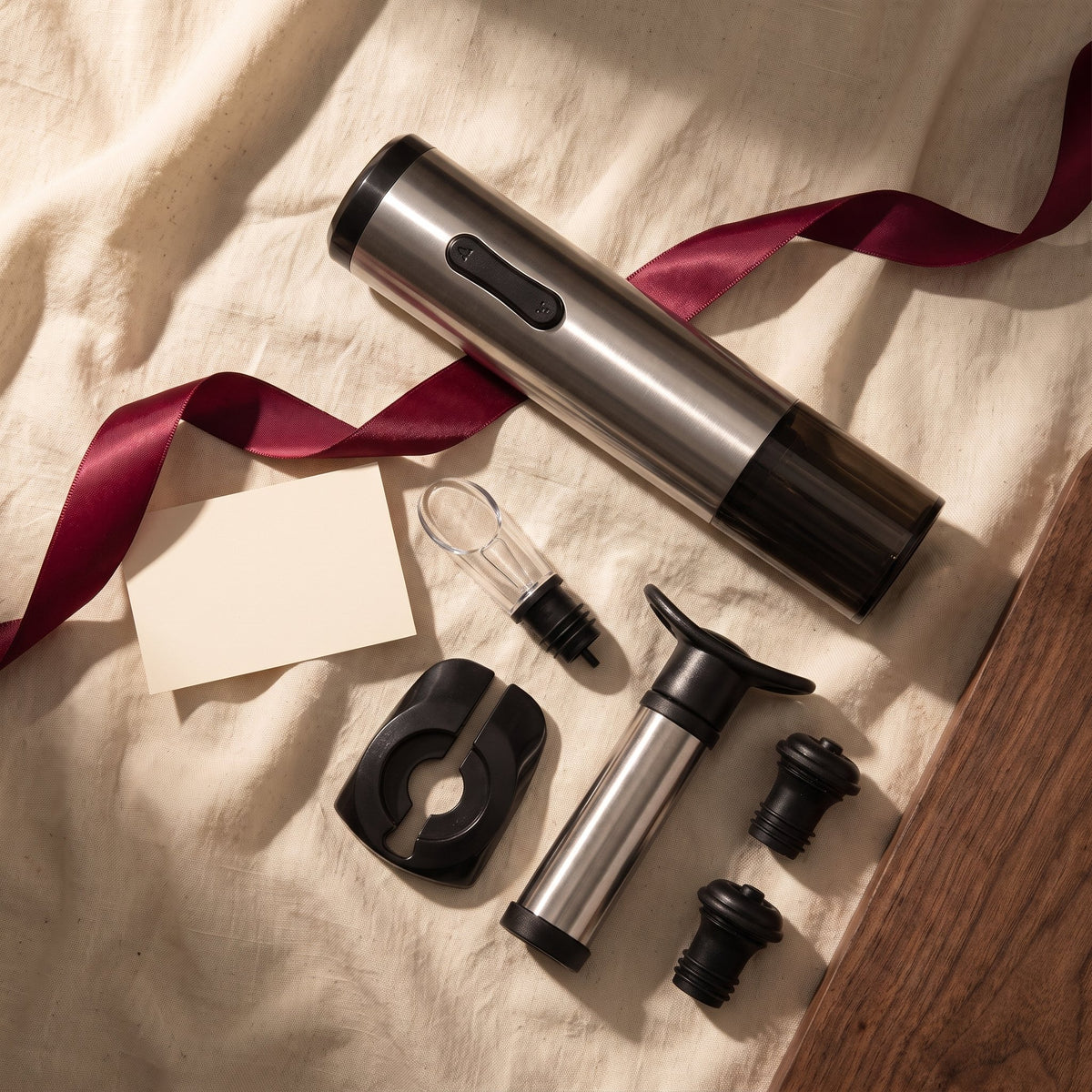 Tire-bouchon électrique et accessoires du coffret sur lin crème avec ruban bordeaux, idée cadeau