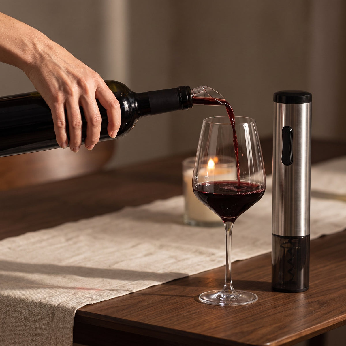 Service du vin avec le bec verseur chromé du coffret, tire-bouchon électrique posé sur la table