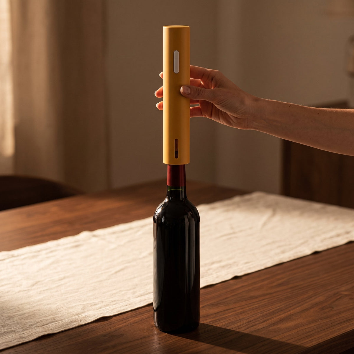 Main posant le tire-bouchon électrique uni jaune sur le goulot de la bouteille — La Maison du Sommelier
