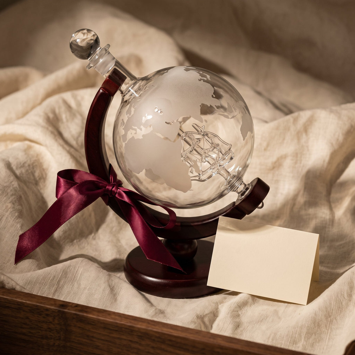 Carafe Globe Trotter avec ruban cadeau bordeaux sur lin crème