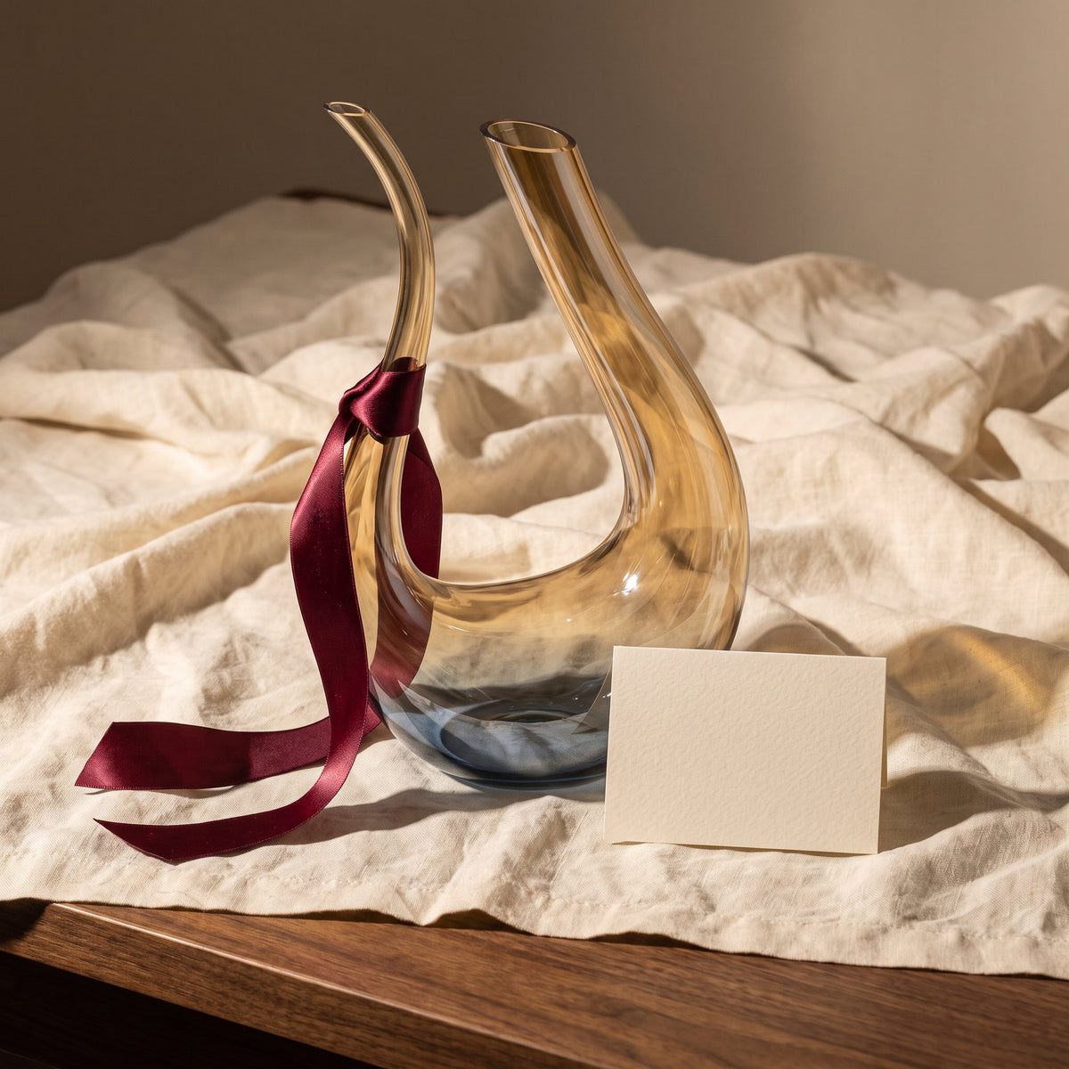 Carafe Cisne Brown avec ruban cadeau bordeaux sur lin crème