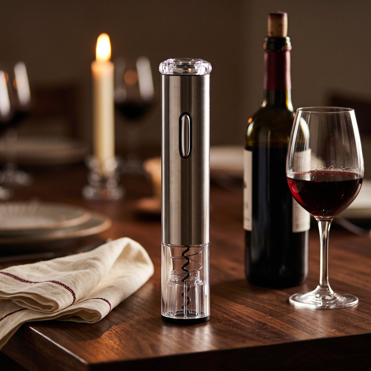 Tire-bouchon électrique avec Batterie sur une table de dîner en noyer avec bouteille et verre de vin rouge
