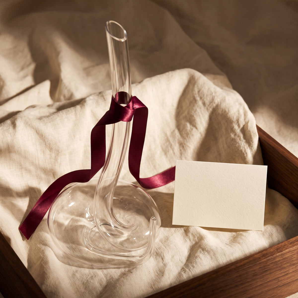 Carafe Cobra avec ruban cadeau bordeaux sur lin crème