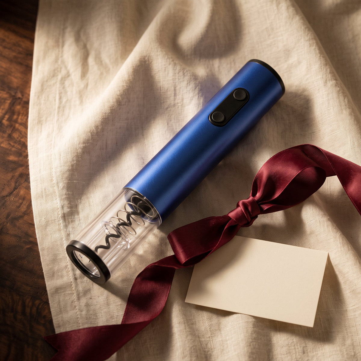 Tire-bouchon électrique Blue Design présenté en cadeau sur lin crème avec ruban bordeaux