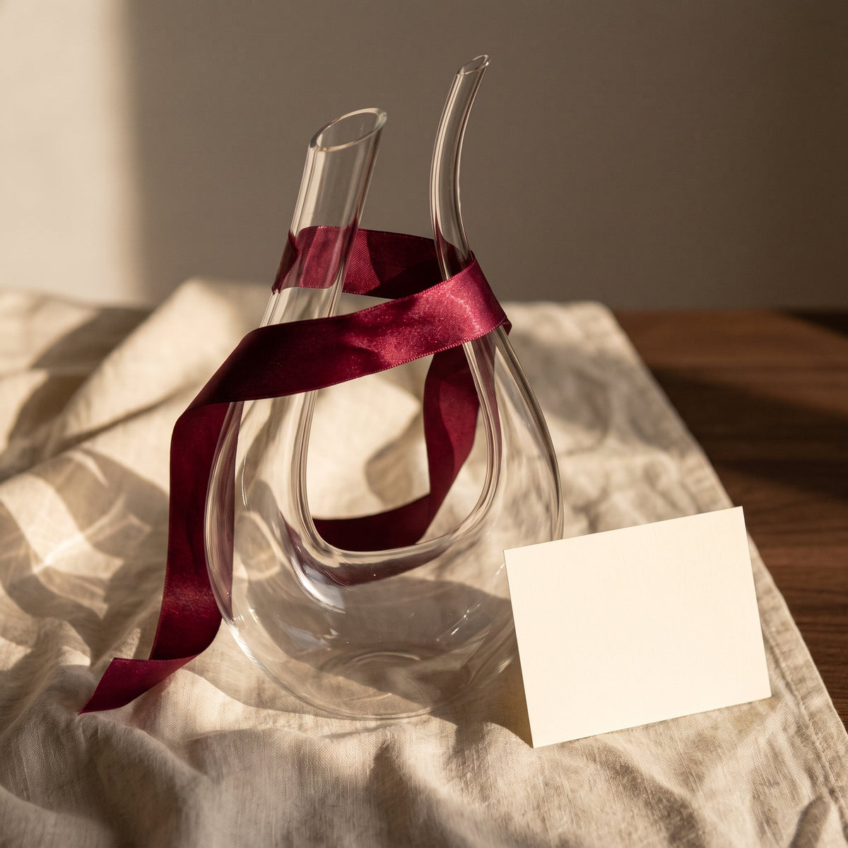 Carafe Cisne avec ruban cadeau bordeaux sur lin crème