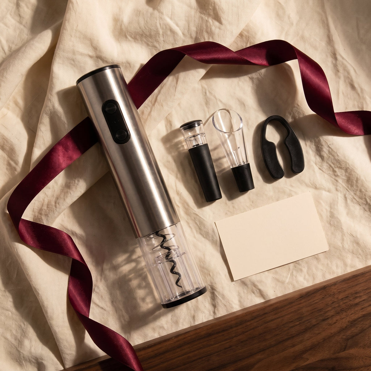 Tire-bouchon électrique gris et accessoires sur lin crème avec ruban bordeaux, idée cadeau