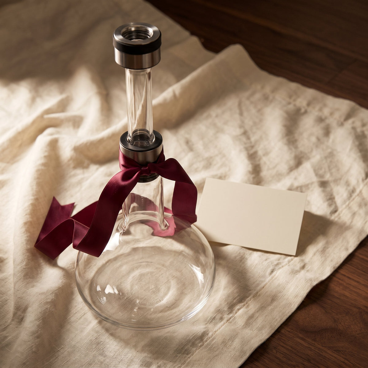 Carafe Up & Down avec ruban cadeau bordeaux sur lin crème
