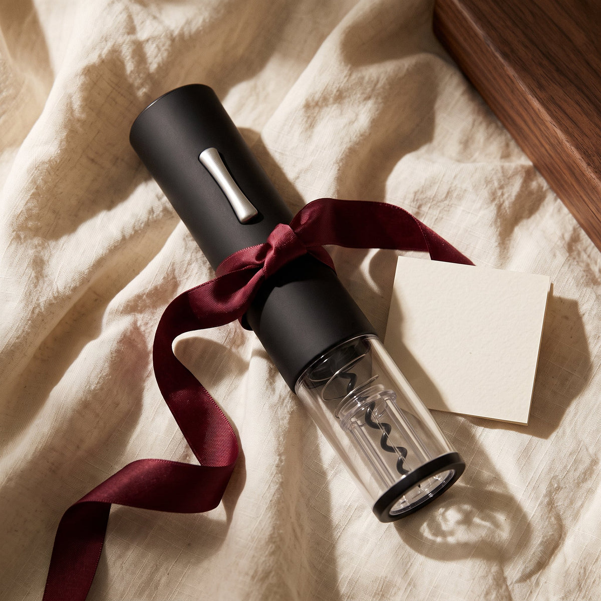 Tire-bouchon électrique Noir Mate présenté en cadeau sur lin crème avec ruban bordeaux