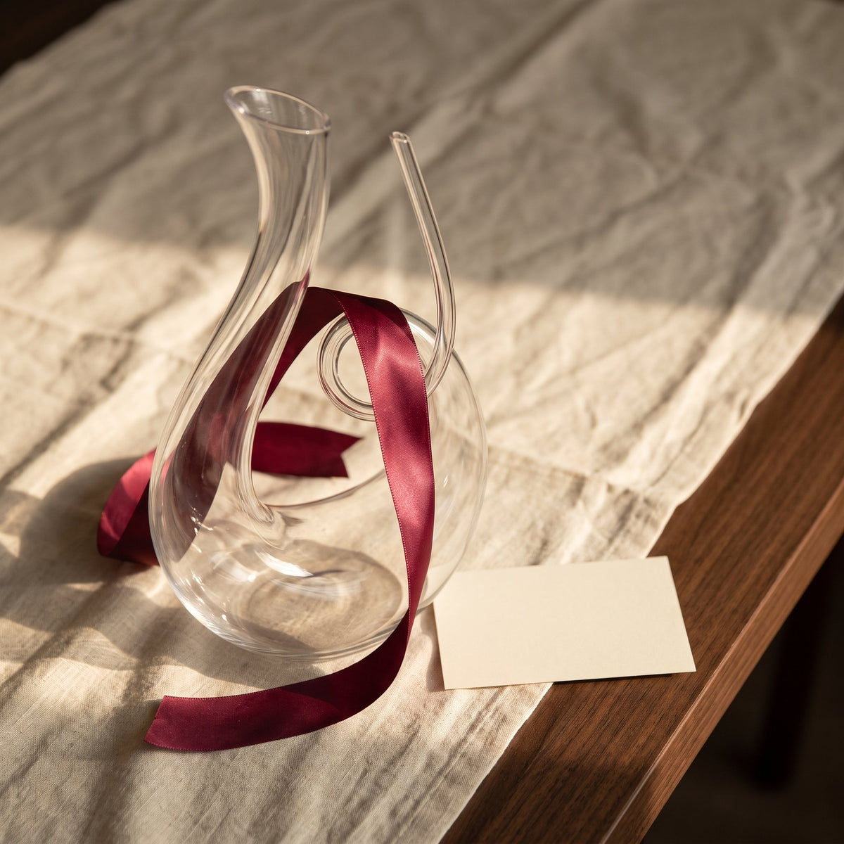 Carafe Sloop avec ruban cadeau bordeaux sur lin crème