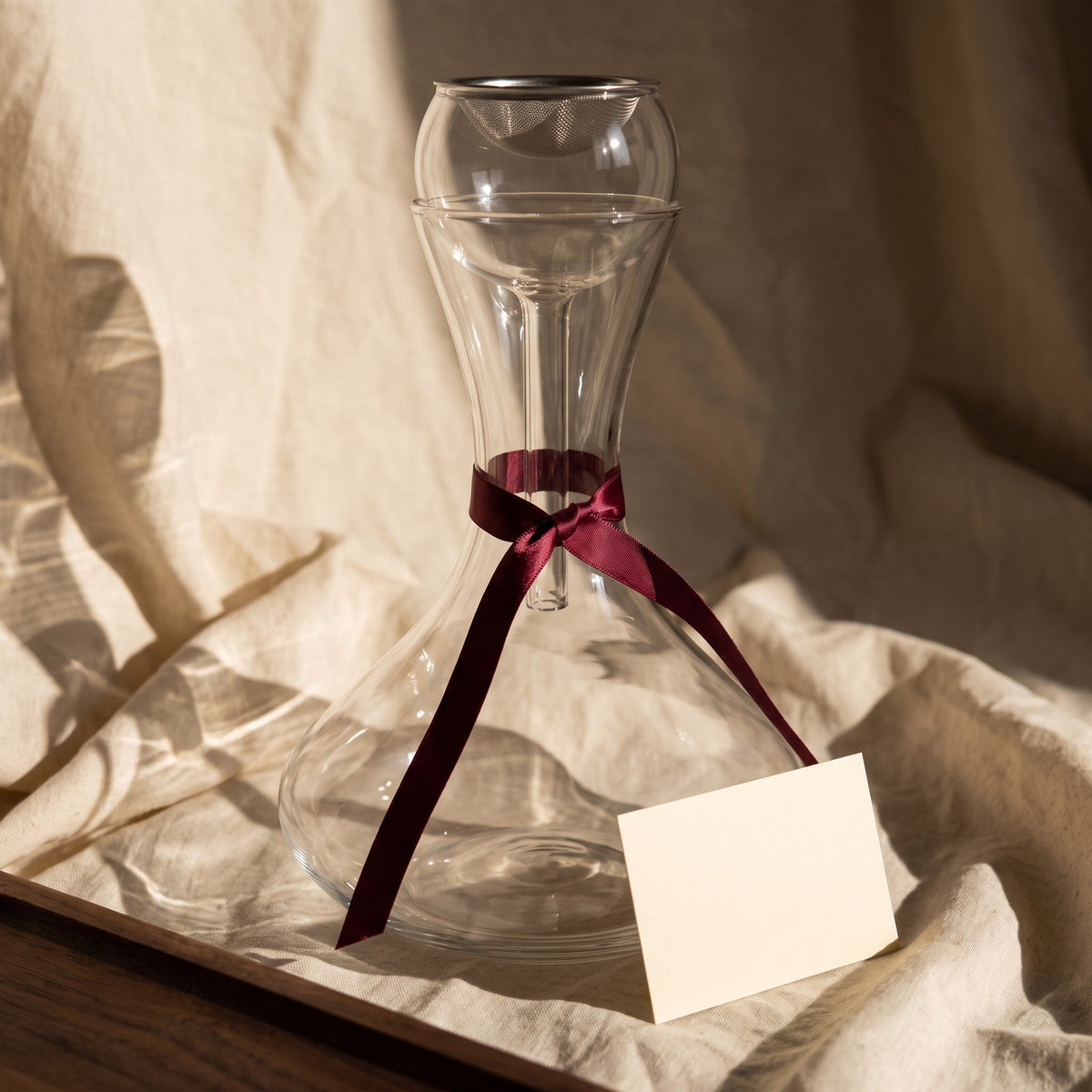 Carafe Nobily avec ruban cadeau bordeaux sur lin crème