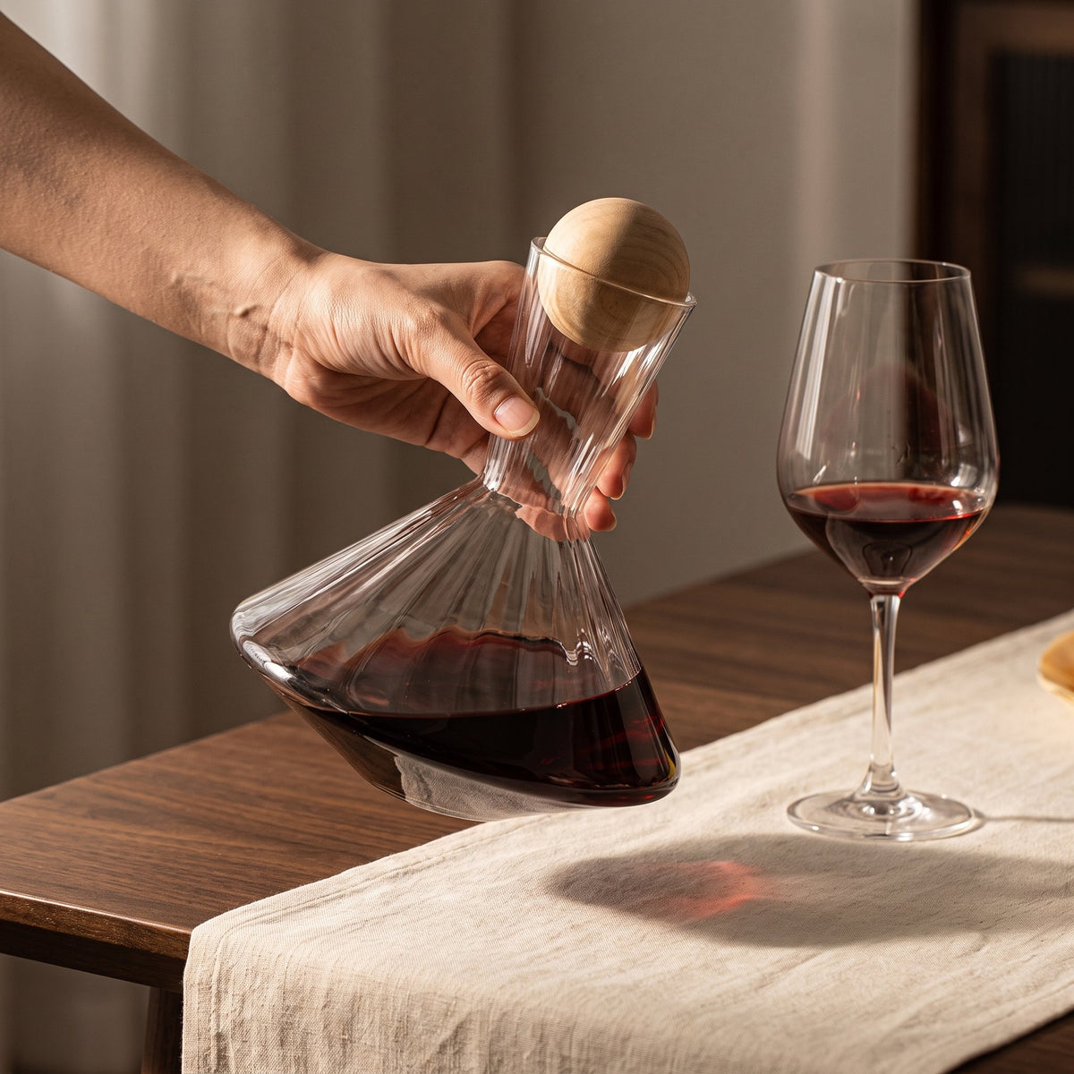 Carafe Spin Cork inclinée tenue en main, vin rouge