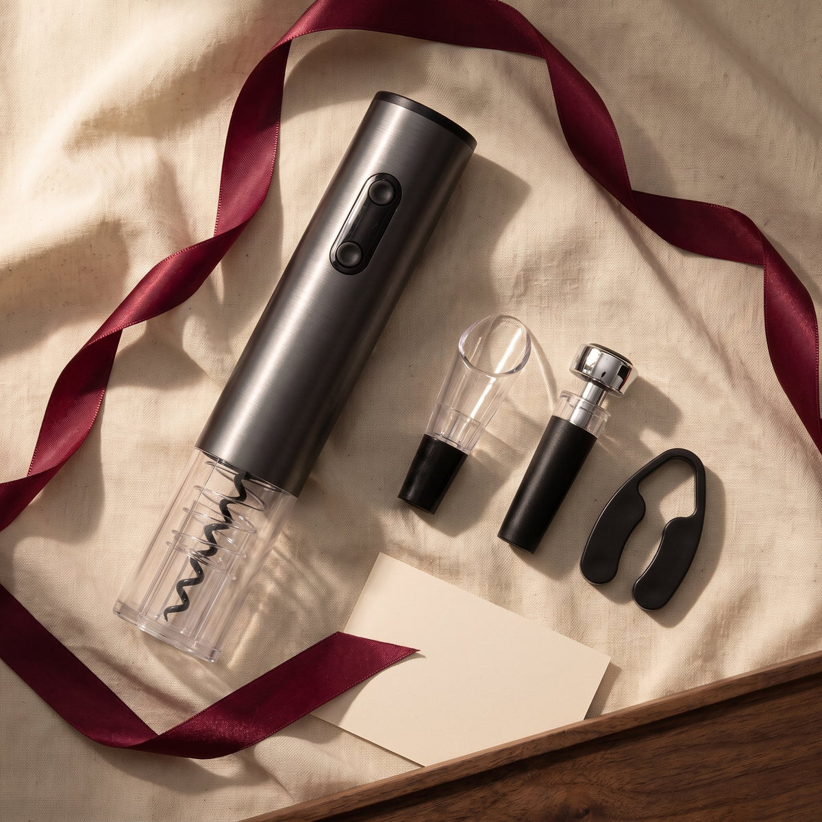 Tire-bouchon électrique et accessoires du coffret sur lin crème avec ruban bordeaux, idée cadeau