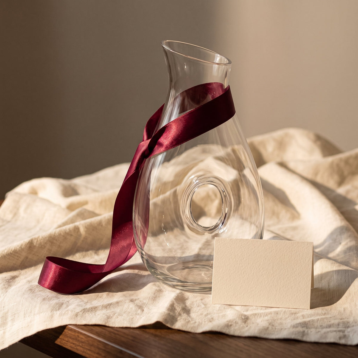 Carafe Hoom avec ruban cadeau bordeaux sur lin crème