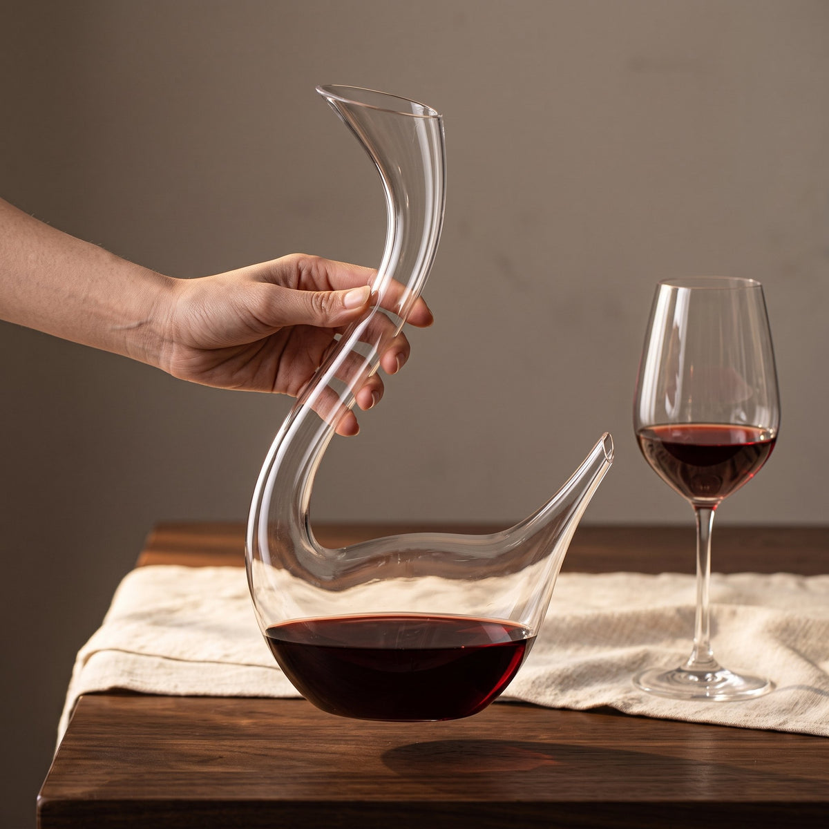 Carafe Cristal Swan tenue en main près d'un verre à pied