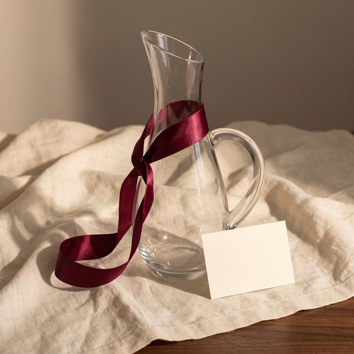 Carafe Lonjeanne avec ruban cadeau bordeaux sur lin crème